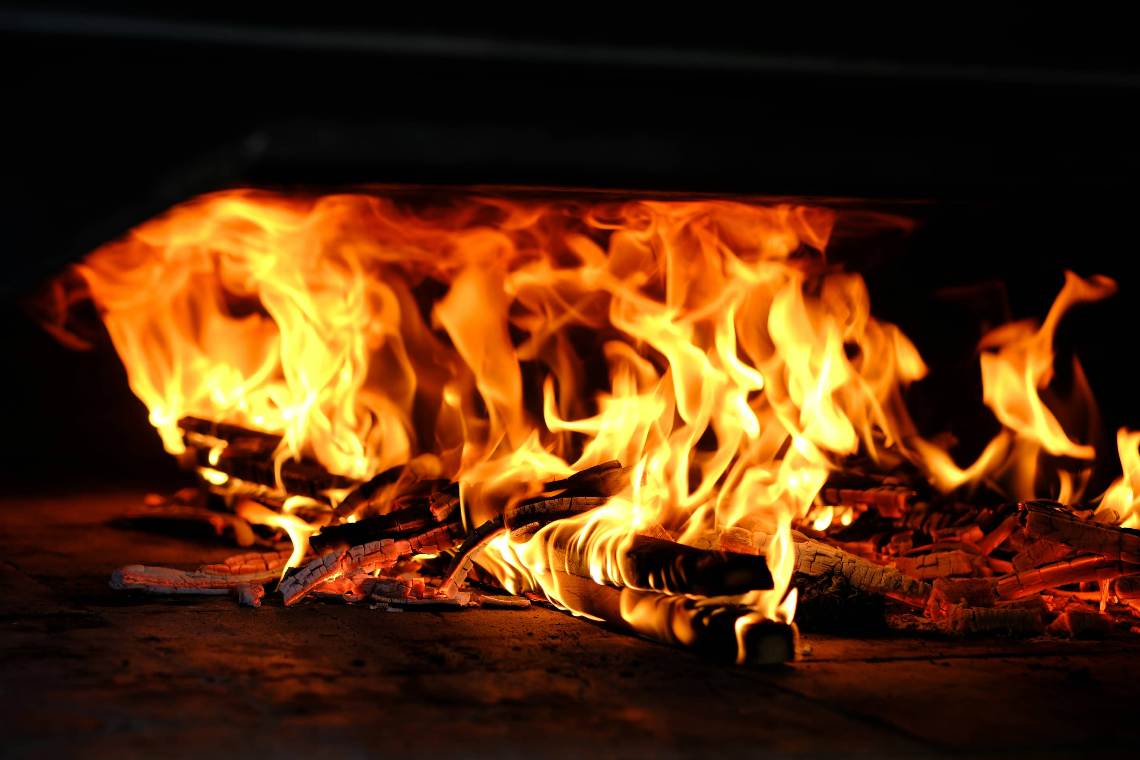 Fiamme e brace vive sul piano del forno, fondo nero