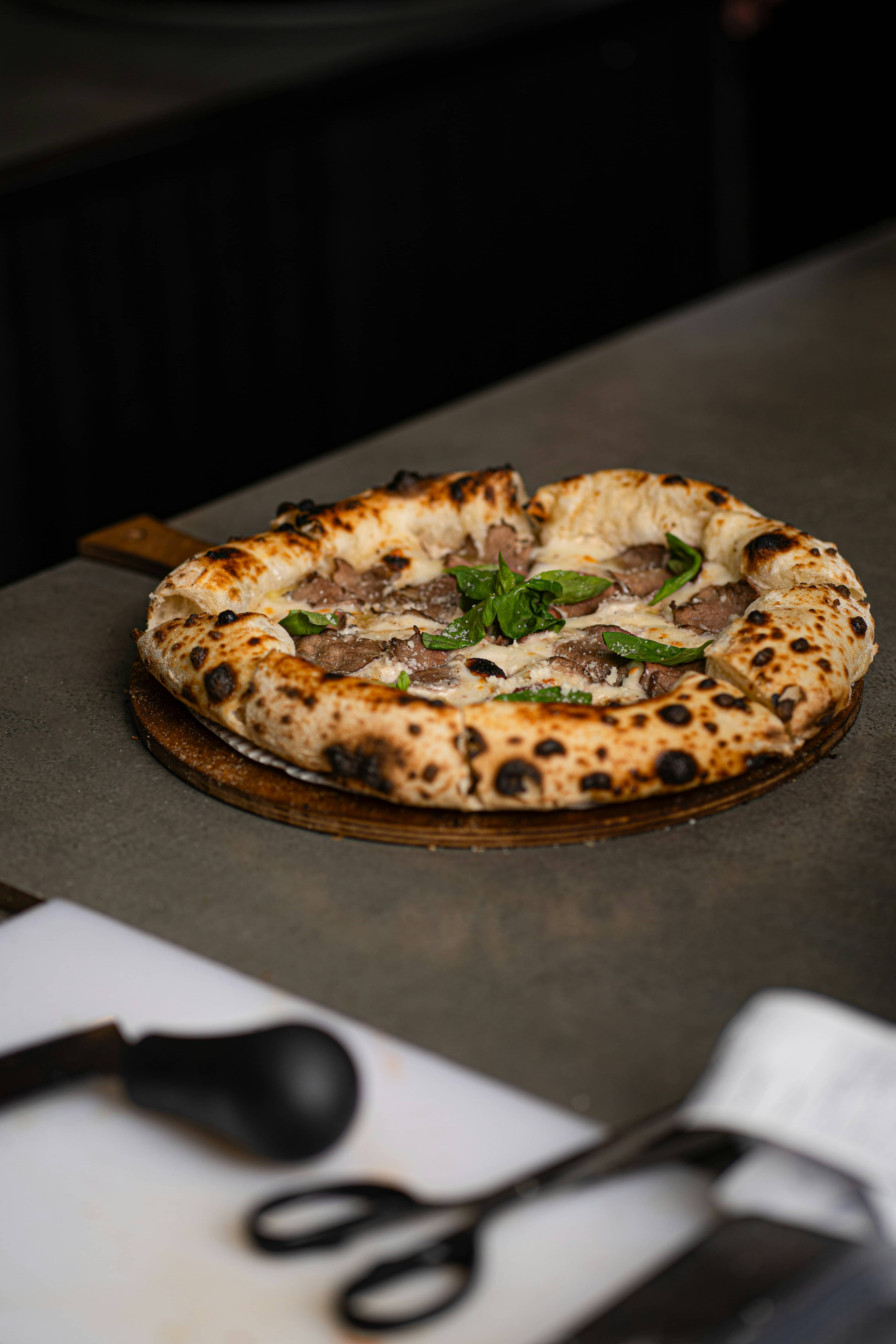 Pizza con carne alla brace e provola sulla pala, al banco di servizio