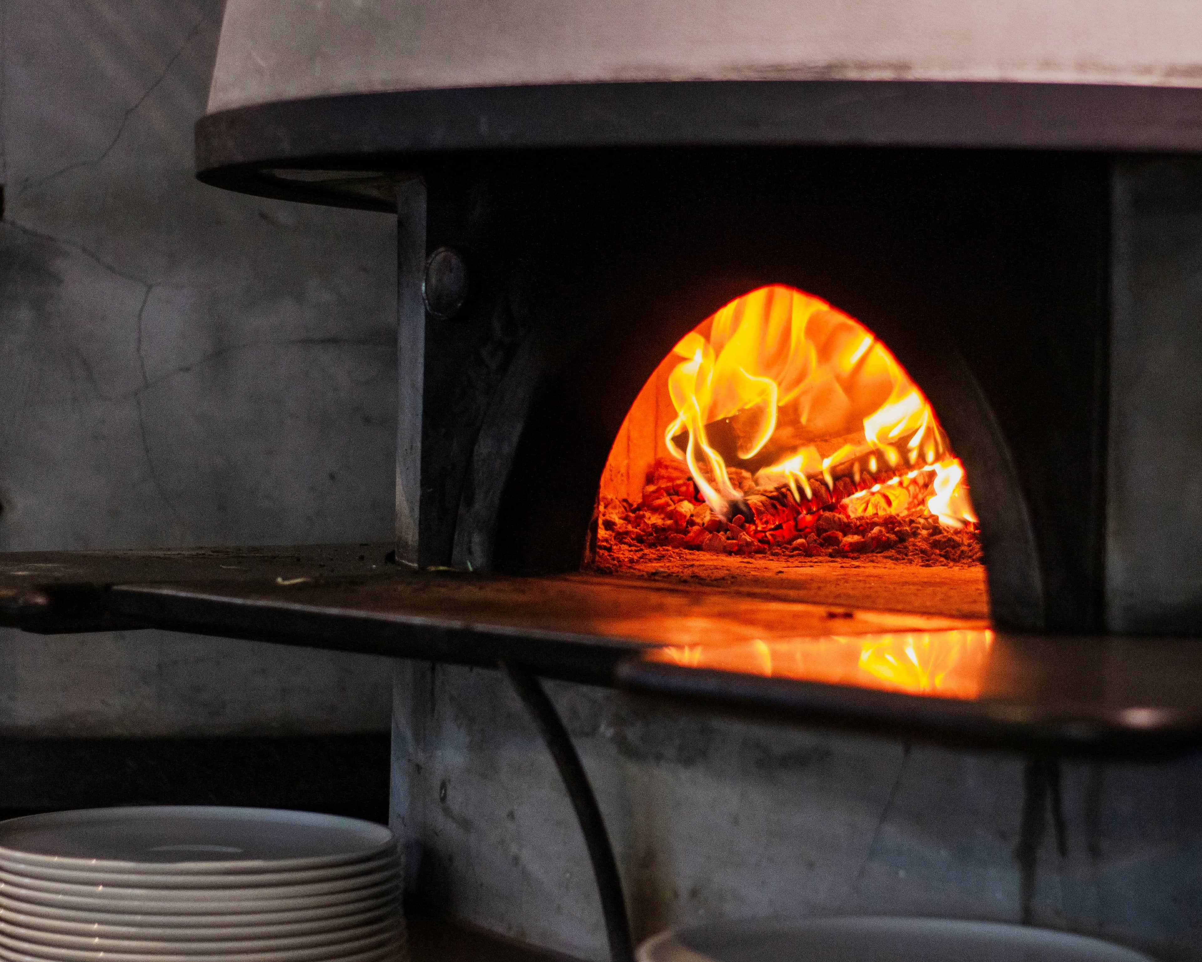 Il forno in cemento al centro del banco, piatti impilati in attesa del servizio